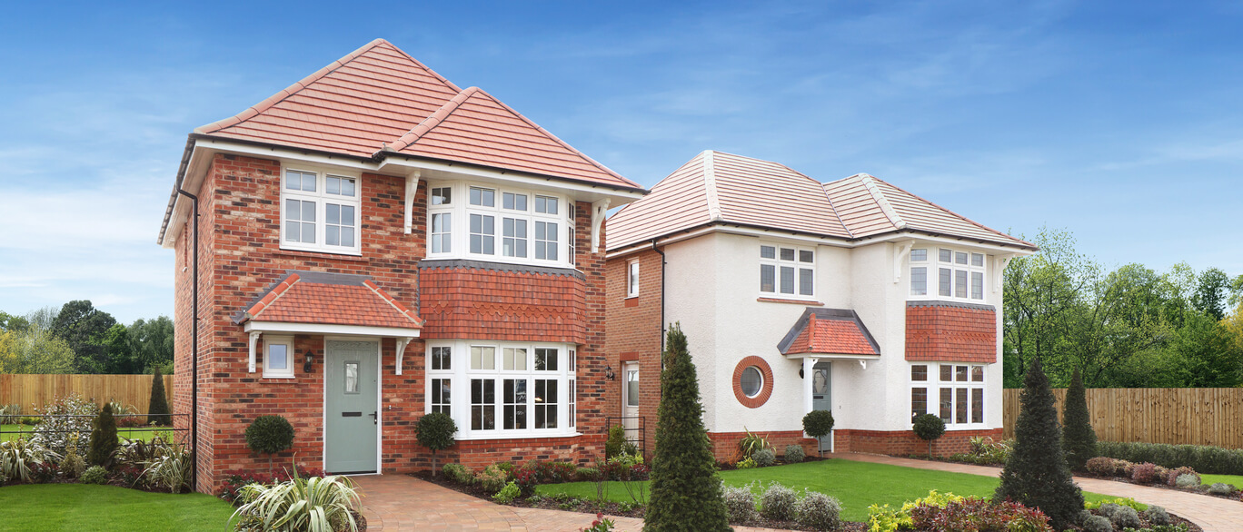 Semi-detached houses with red brick and white walls, large windows, and well-maintained front gardens under a blue sky.