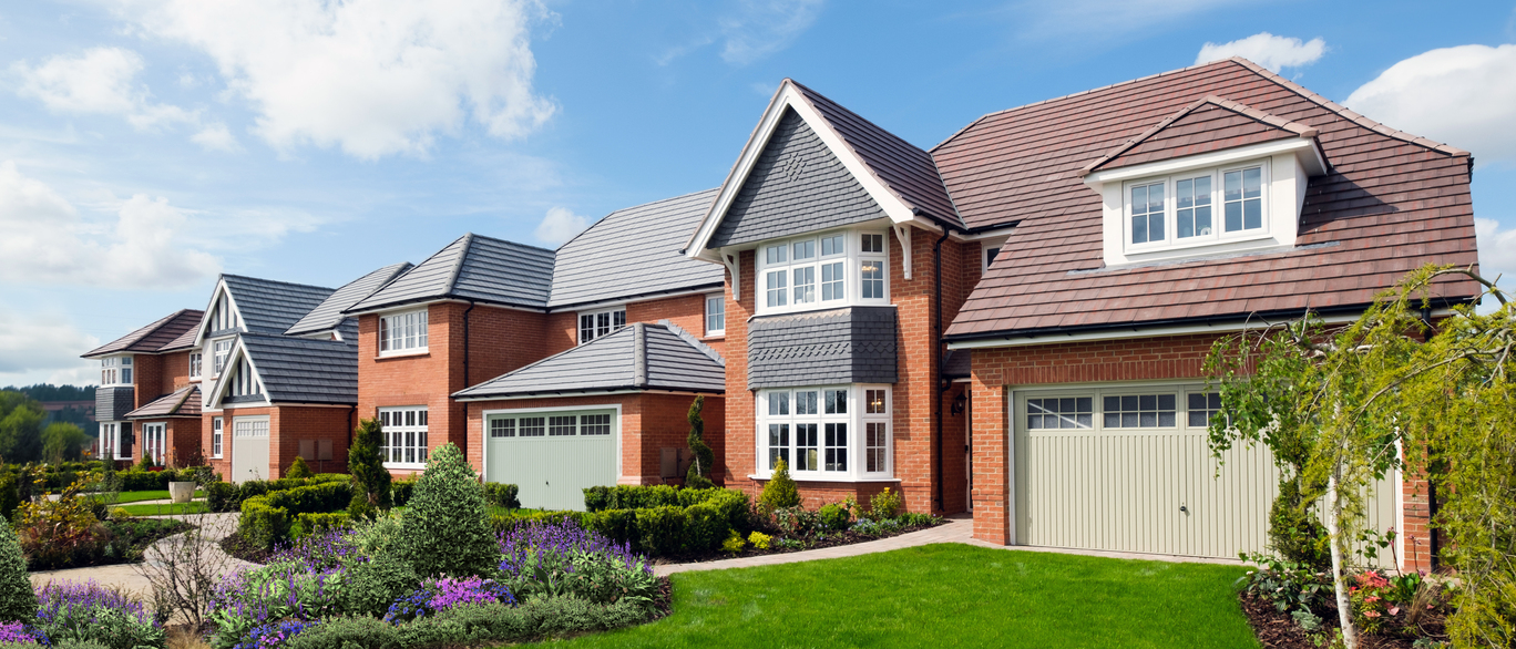 A row of modern red-brick houses with grey and brown tiled roofs, white-framed windows, and well-maintained gardens under a blue sky with fluffy clouds at Churchlands