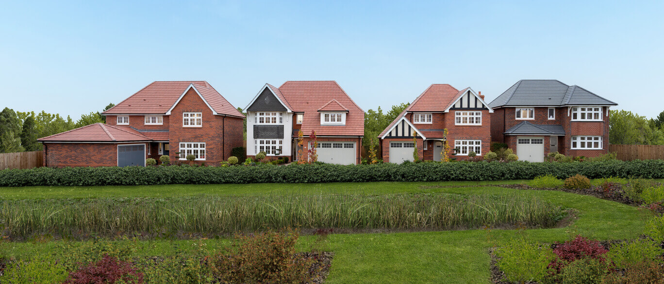 A row of modern detached houses with brick exteriors and pitched roofs, surrounded by greenery and a well-maintained lawn at Hazel Park.