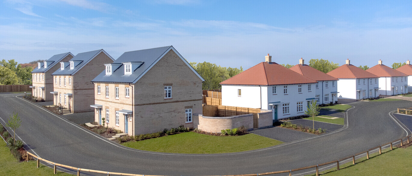 Newly built semi-detached and detached houses with well-maintained gardens and curved asphalt roads in a modern residential area at The Foxgloves at Meadow View.