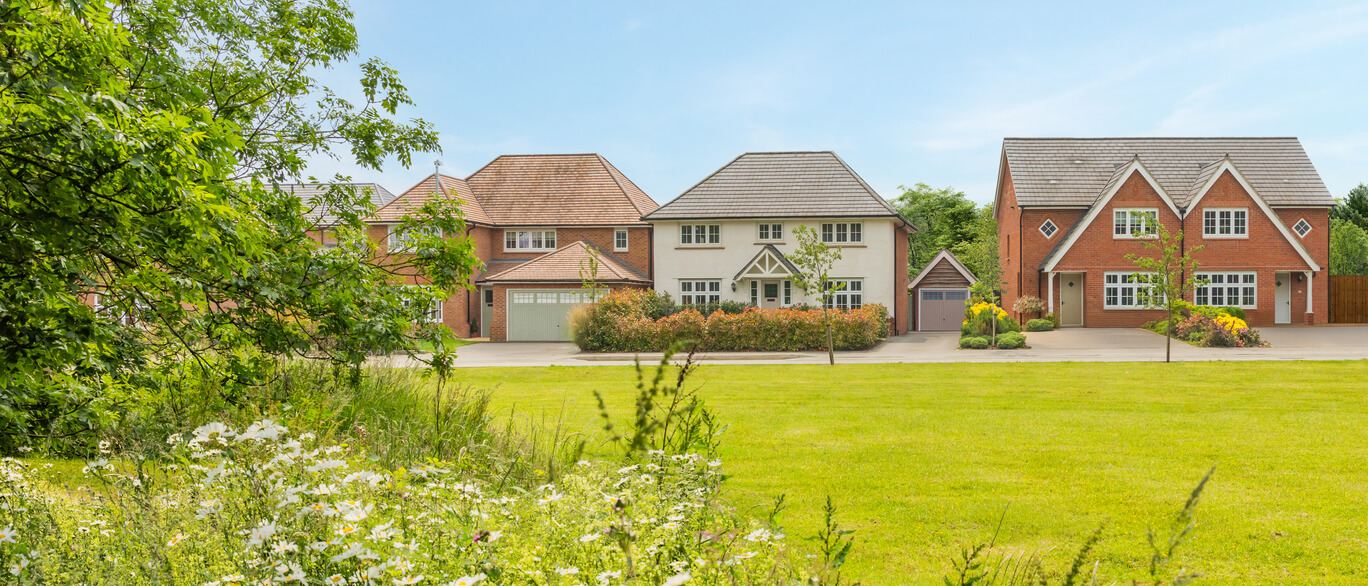 Three modern detached houses with well-maintained lawns and trees in a suburban neighbourhood under a blue sky at Amington Fairway.