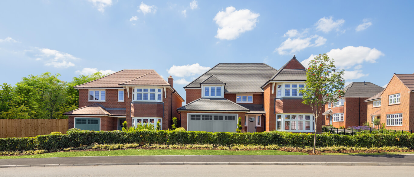 A row of modern detached houses with brick exteriors and well-maintained gardens under a blue sky with scattered clouds at Royal Gardens at Kensington Gate.