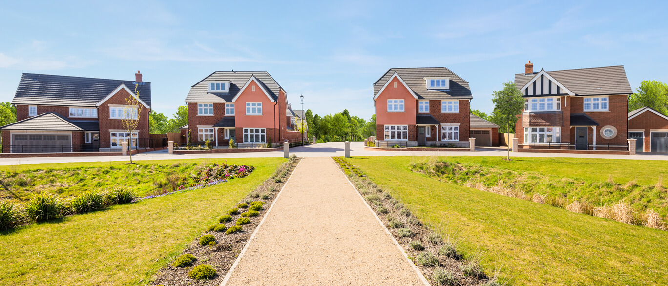 Modern suburban houses with well-maintained gardens and a central pathway in a sunny neighbourhood at Blossoms, Round Hill Gardens.