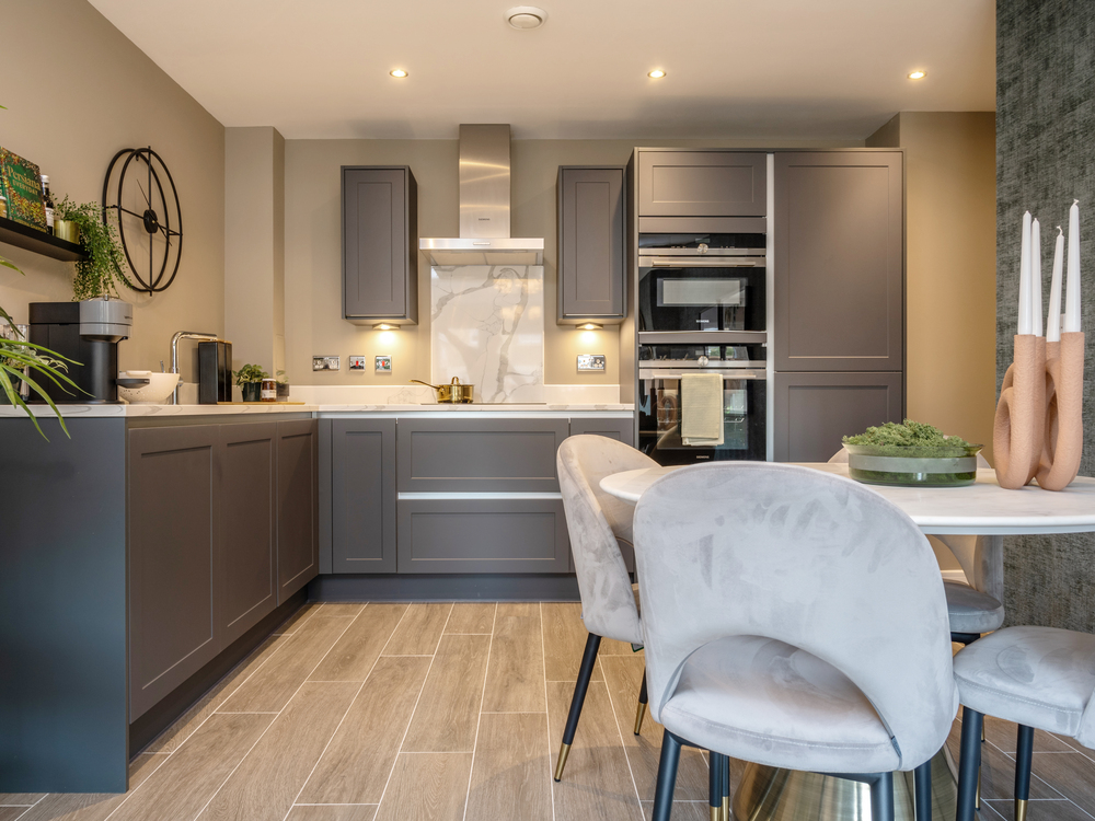 Image showcasing the stylish midnight blue kitchen with dining table and 4 chairs in the open-plan layout of an apartment at Stonehaven Park