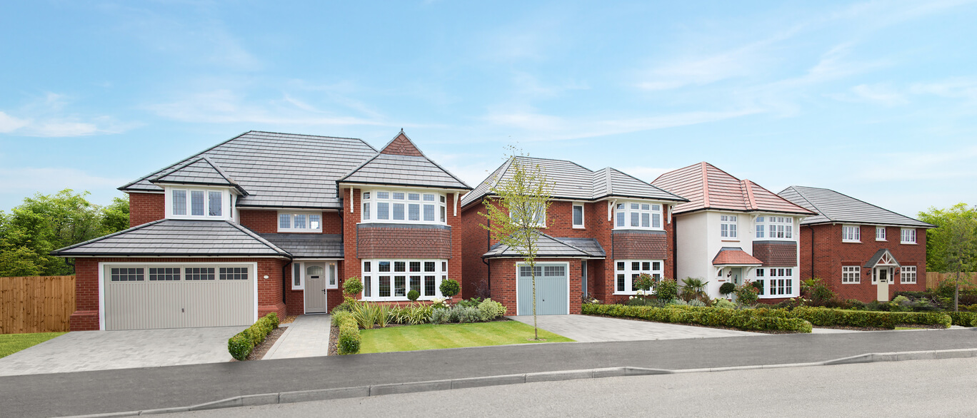 A row of modern detached houses with brick and white exteriors, bay windows, and neatly maintained front gardens on a sunny day at Pilgrims Chase.