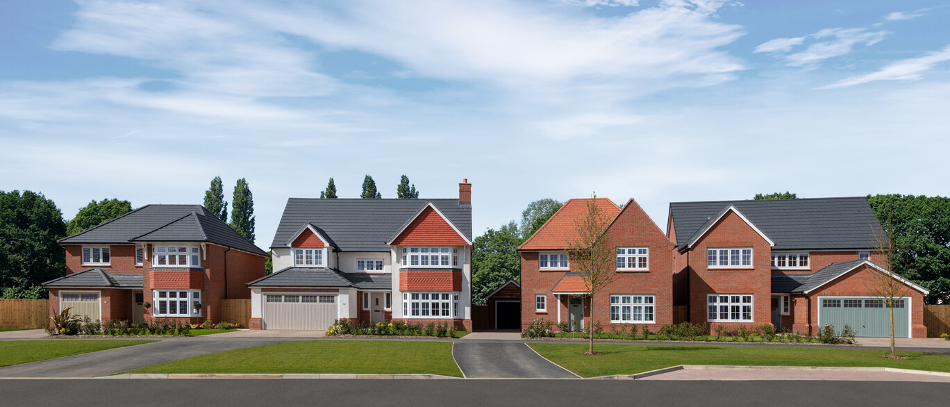 A row of modern detached brick houses with grey roofs under a blue sky and green trees in the background at The Maltings.