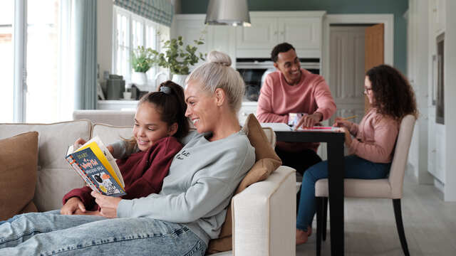 Family reading together in open plan kitchen dining family room