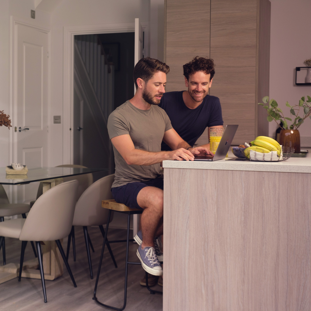 Couple on laptop in kitchen next to double open doors into the garden