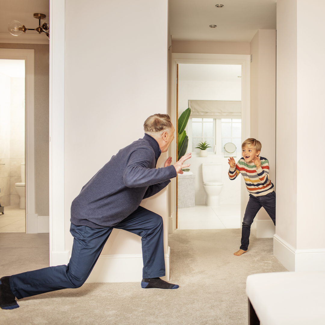Grandfather and grandson playing hide and seek in bedroom