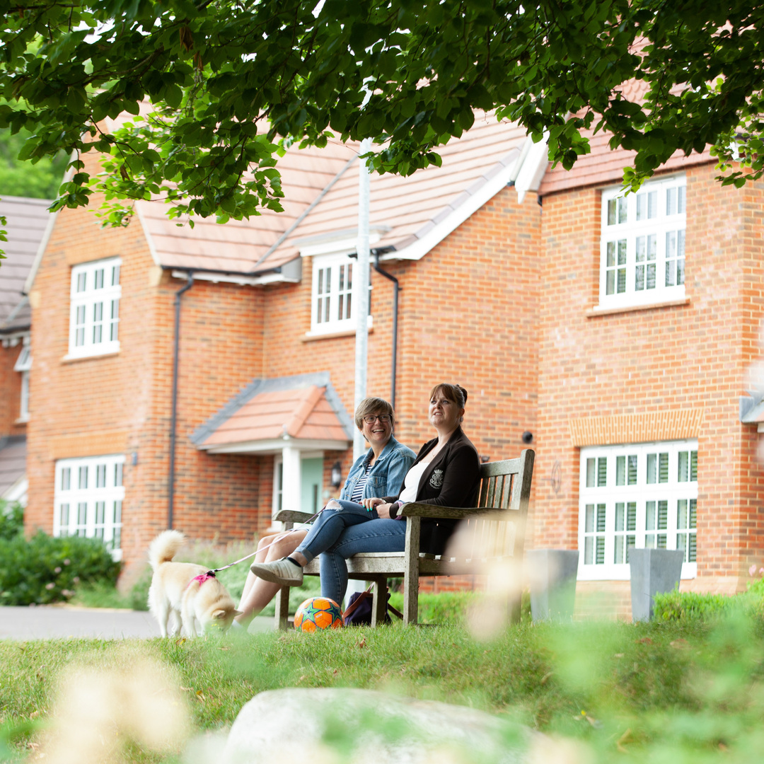 2 friends sat on bench by Redrow homes