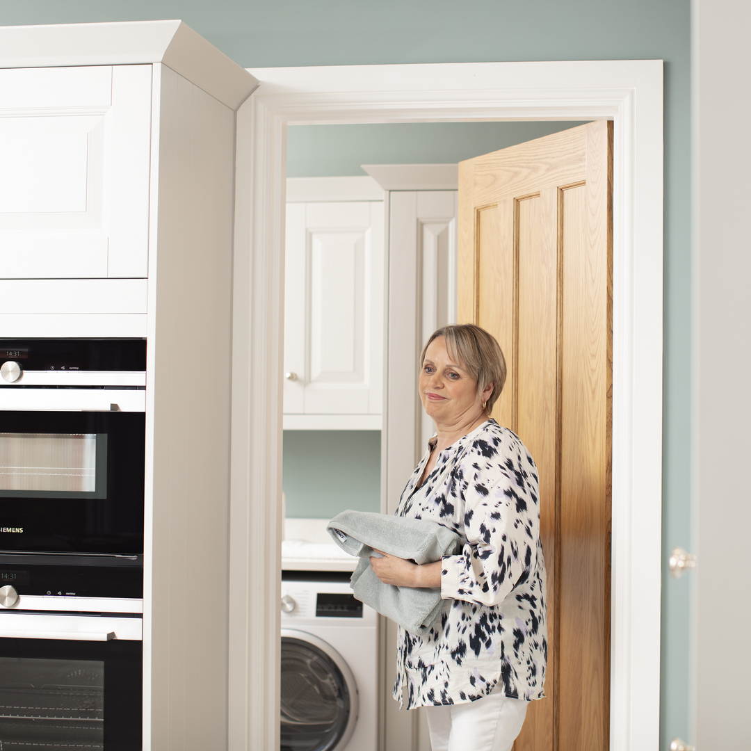 Woman carrying towel from laundry room into kitchen