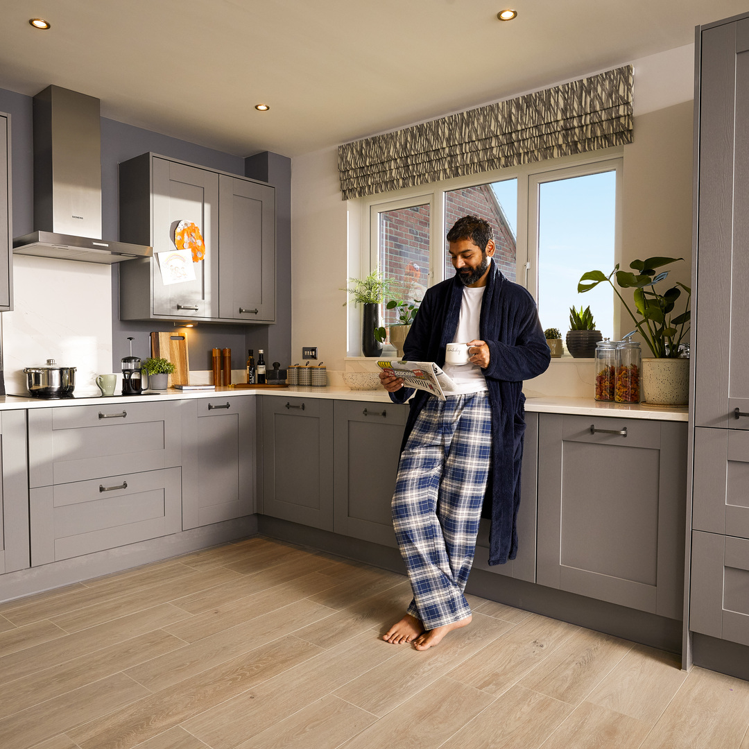 Man reading morning paper in the kitchen with bare feet
