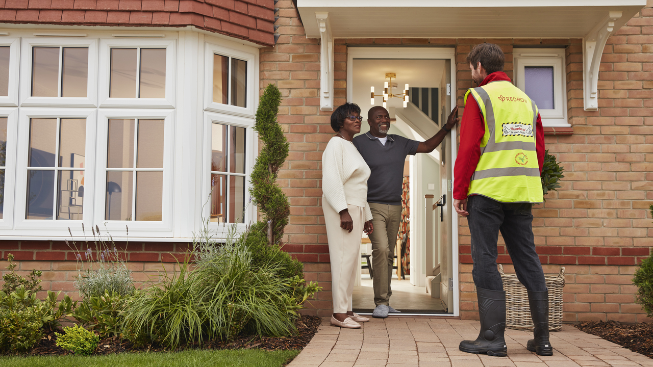 Construction worker greets couple at the door of a Redrow home