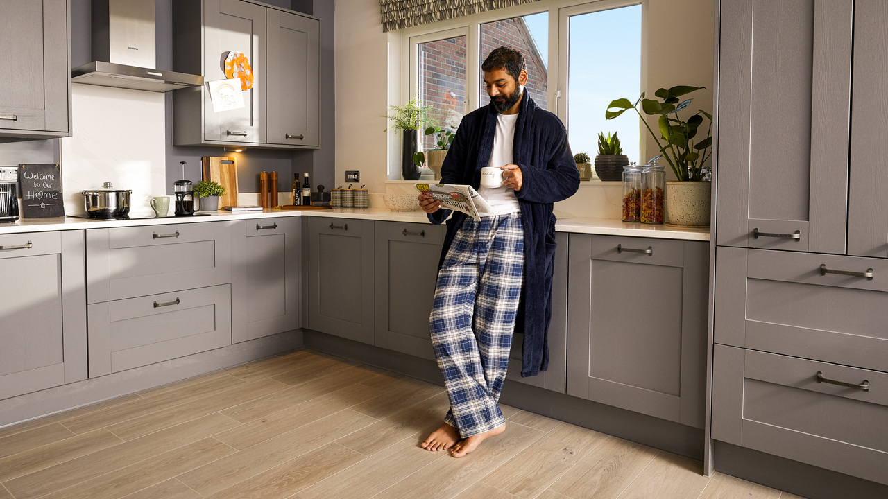 Man reading paper in kitchen barefoot