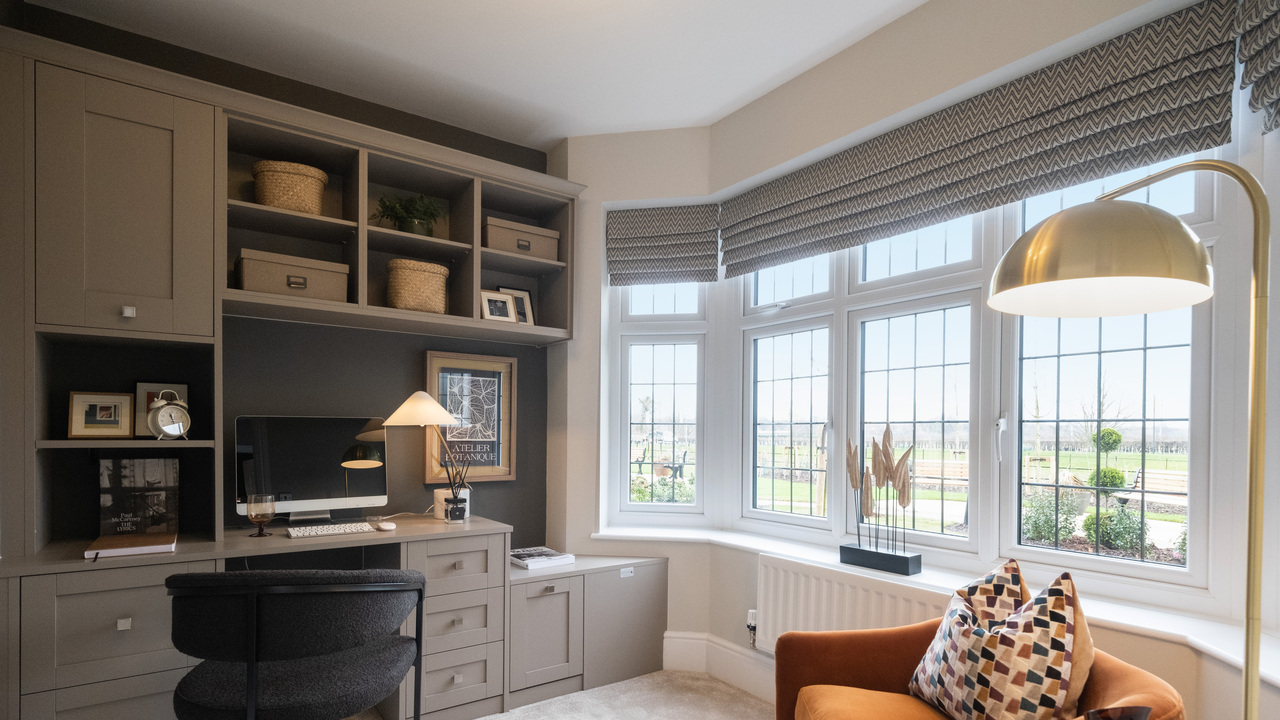 Home office with built in units, large window and orange reading chair