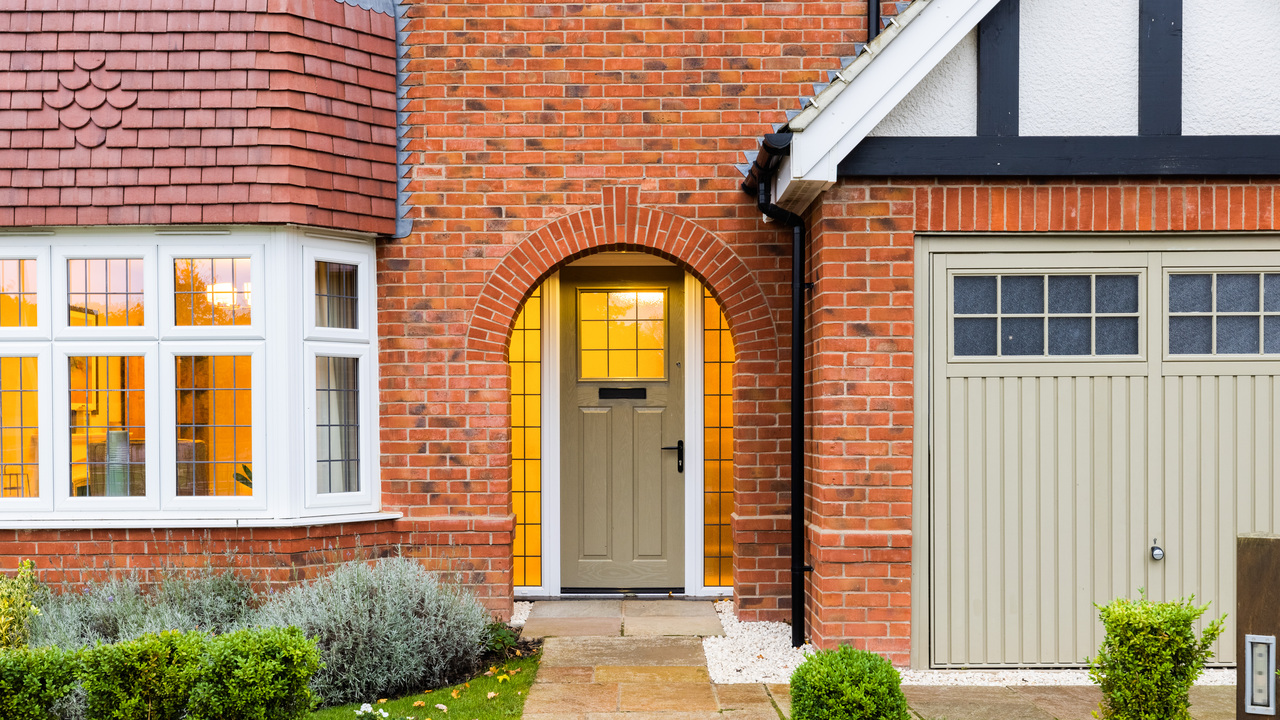 Sage green door in an arched doorway, with warm light glowing from the inside