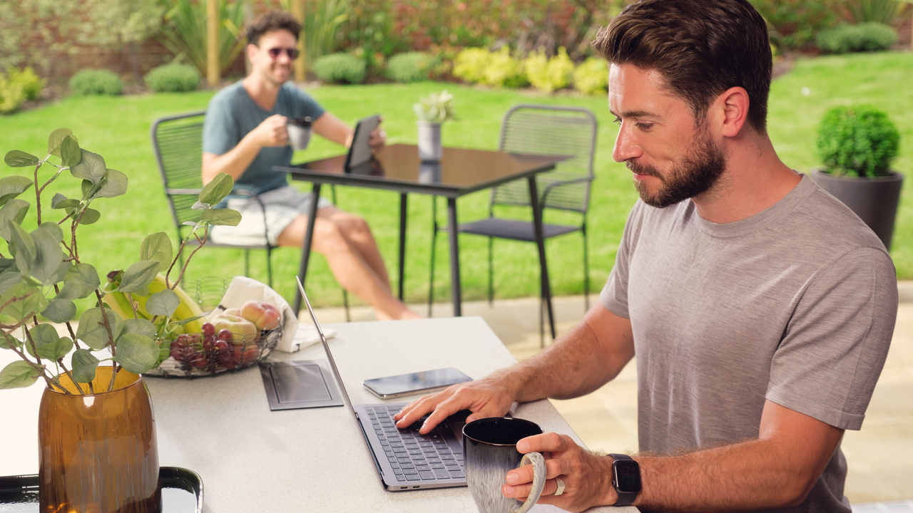 Two men drinking coffees in their garden searching for new homes on their devices