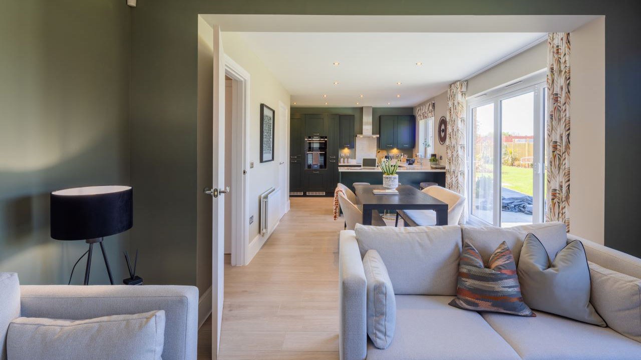 A stylish, open-plan kitchen, dining and family area with dark walls and a beige sofa