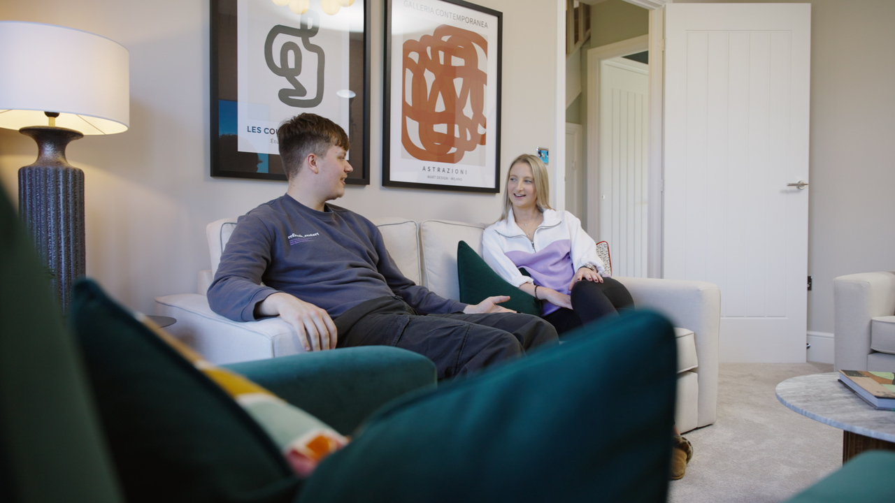 A chatting couple sitting on the sofa at a Redrow Customer Experience Suite