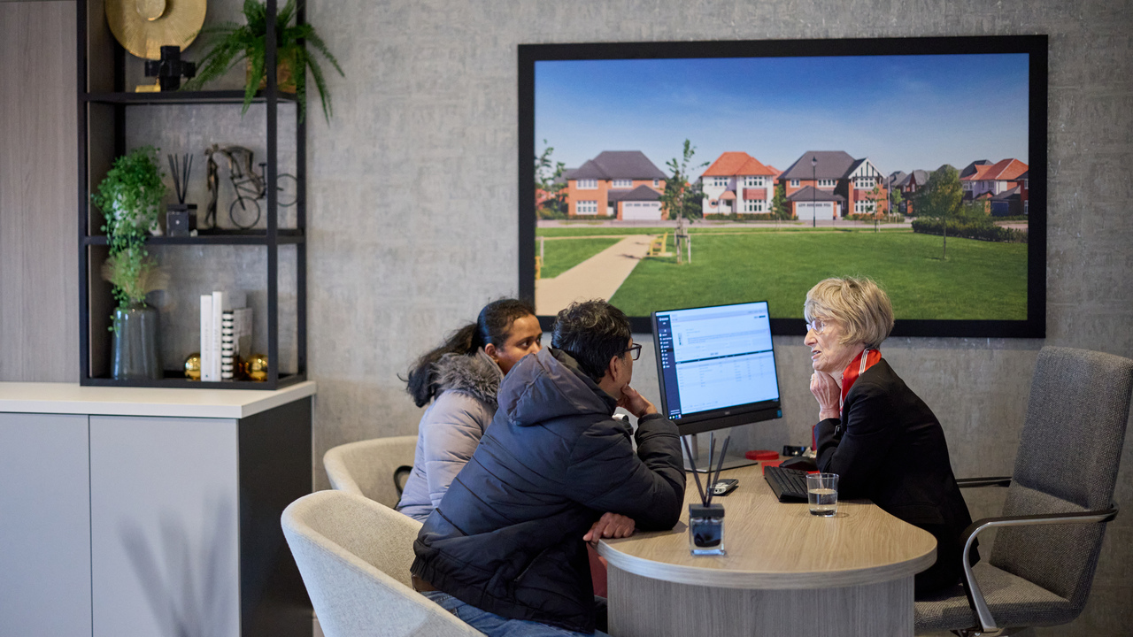 A couple and a Redrow Sales Advisor looking at a computer screen in the Customer Experience Suite