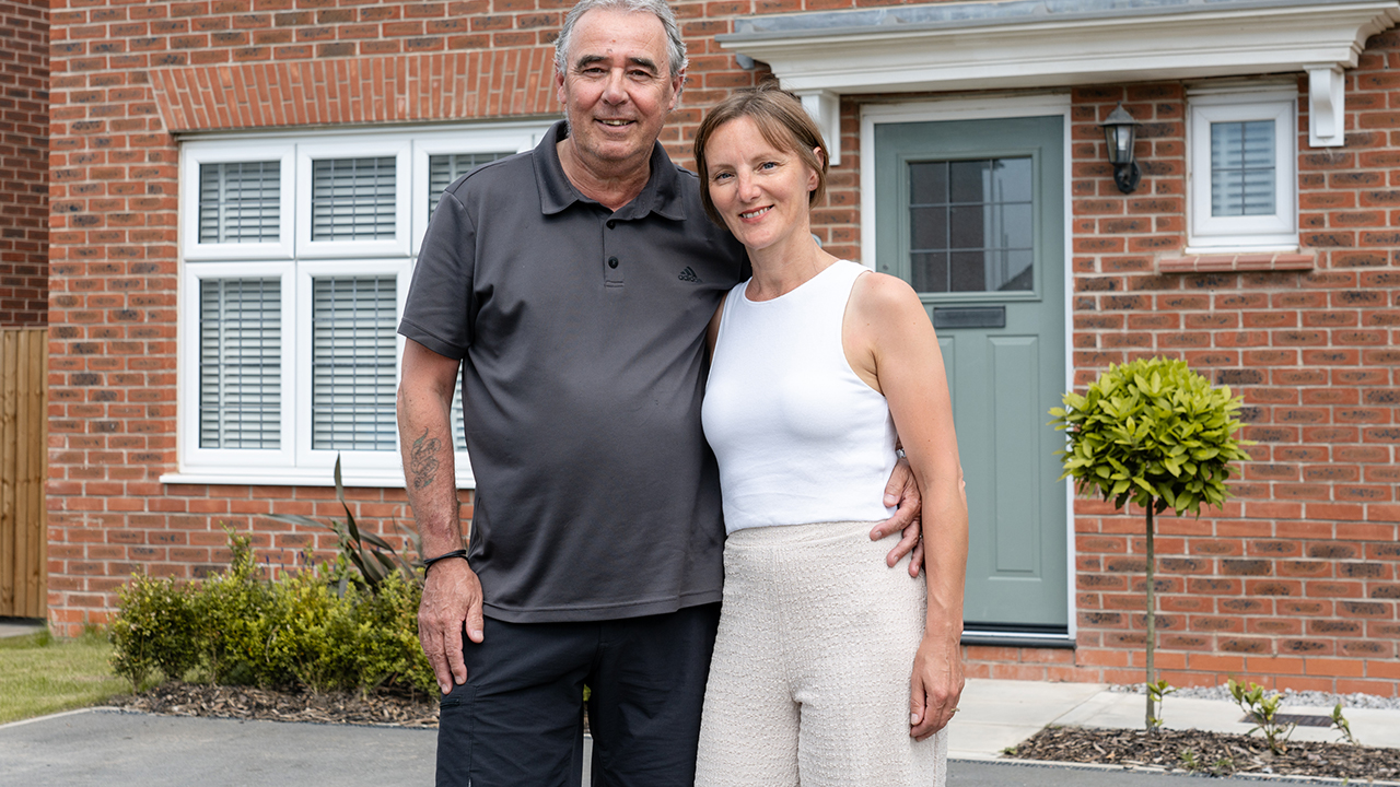 Couple standing in front of a house with a sage green door