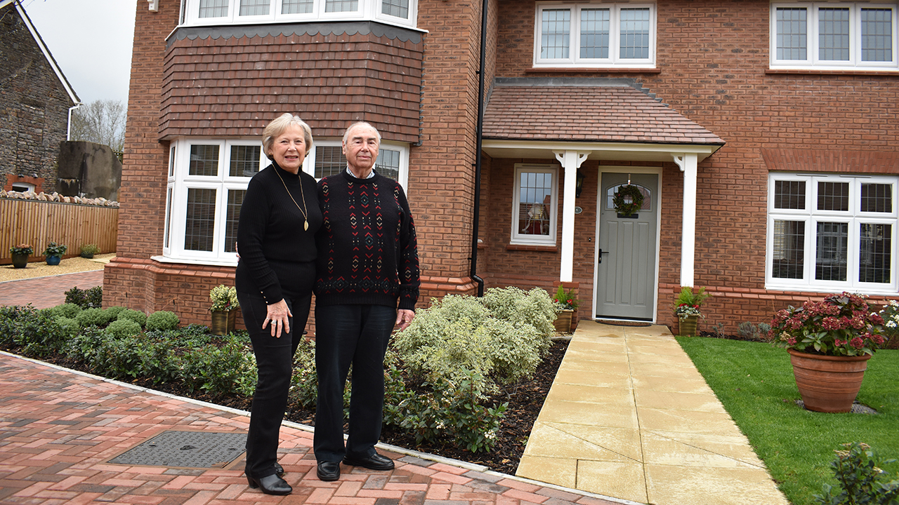 A couple standing proudly outside their new Redrow home