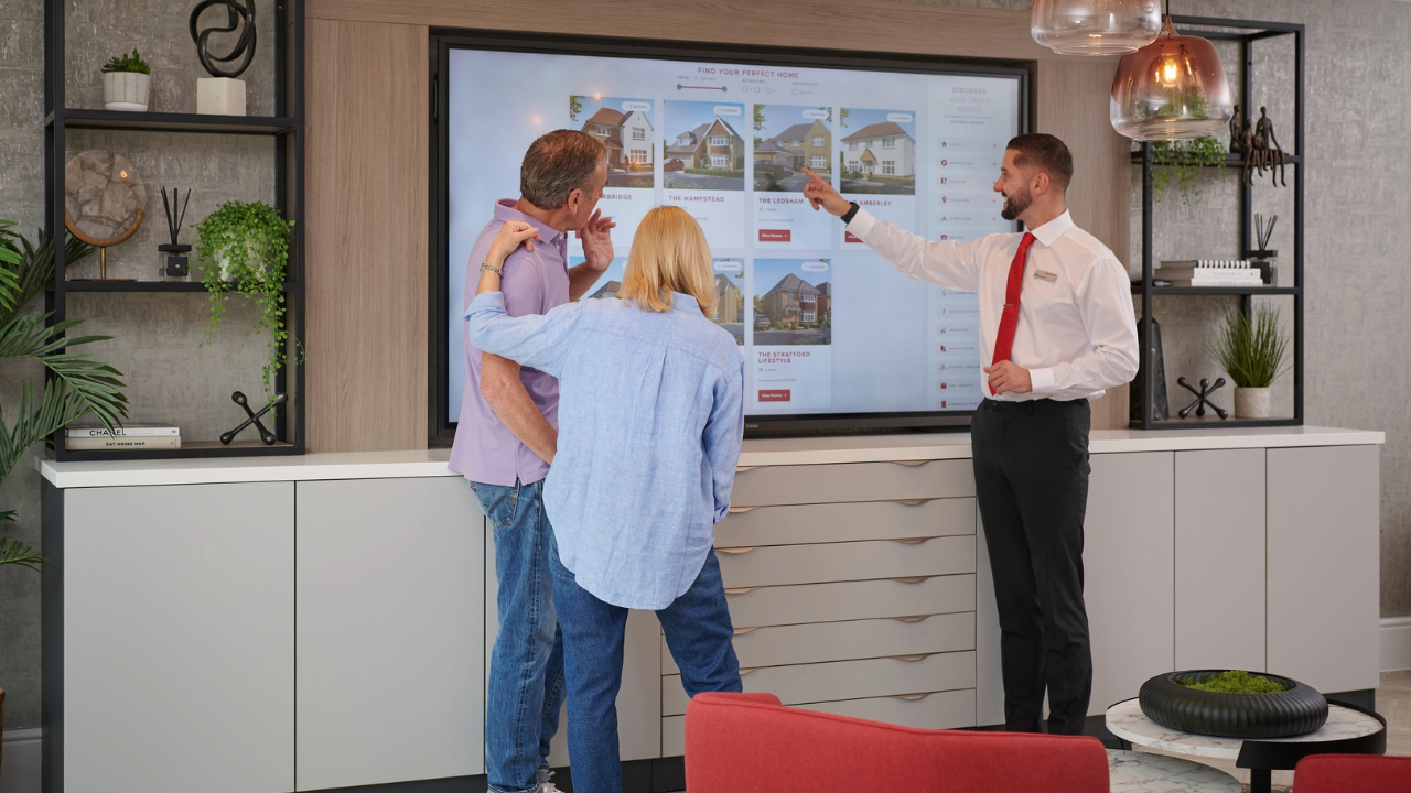 A Redrow Sales Consultant showing a couple properties on a large screen