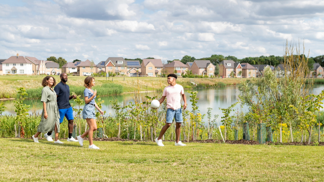 Friends walking past a large body of water holding a ball