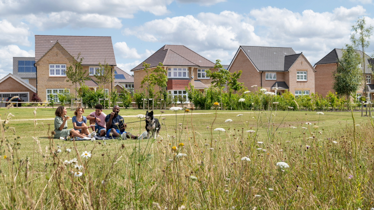 Family picnic in a field overlooked by Redrow homes