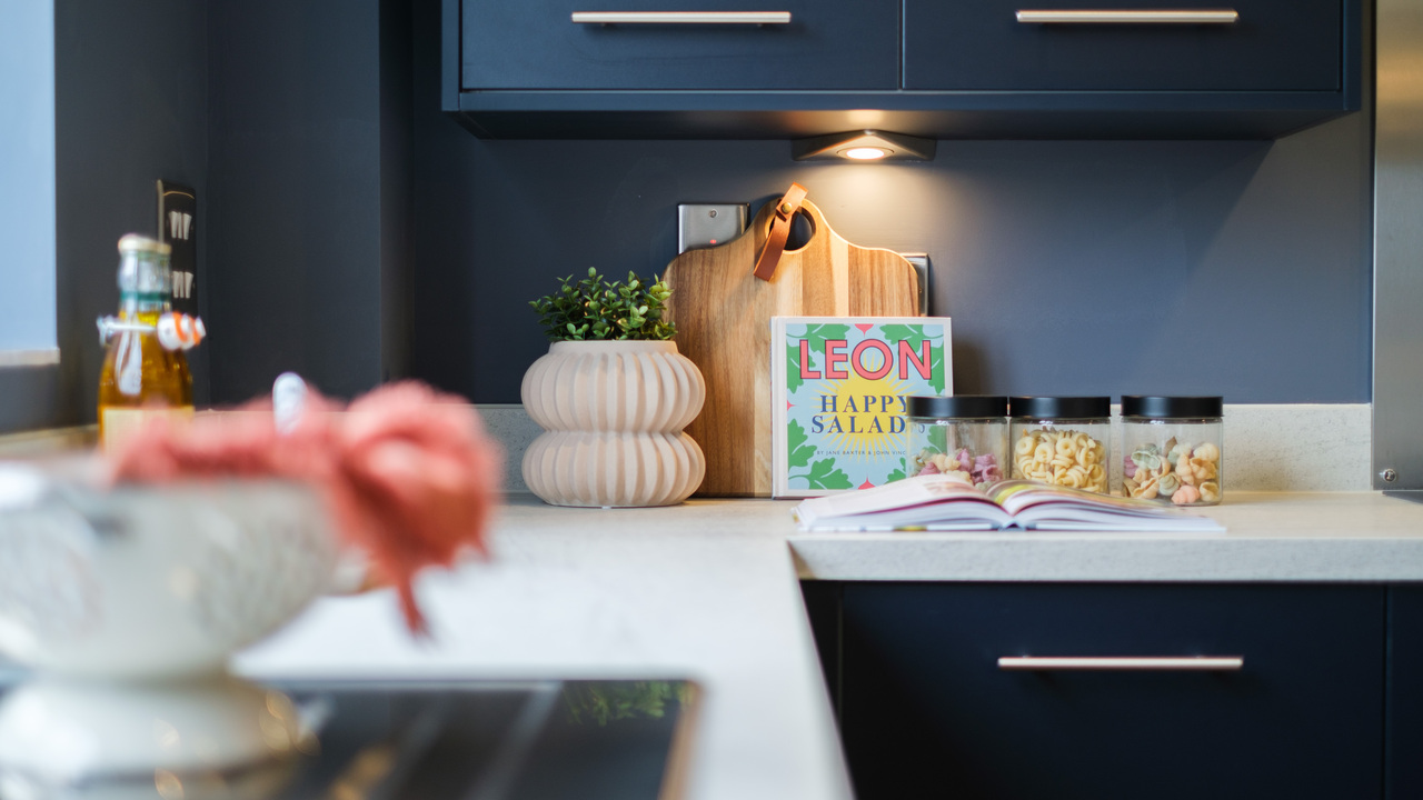 Navy kitchen with an under unit light shining on some stylish accessories