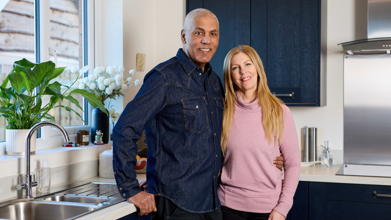 Couple standing in navy kitchen with plants on the windowsill
