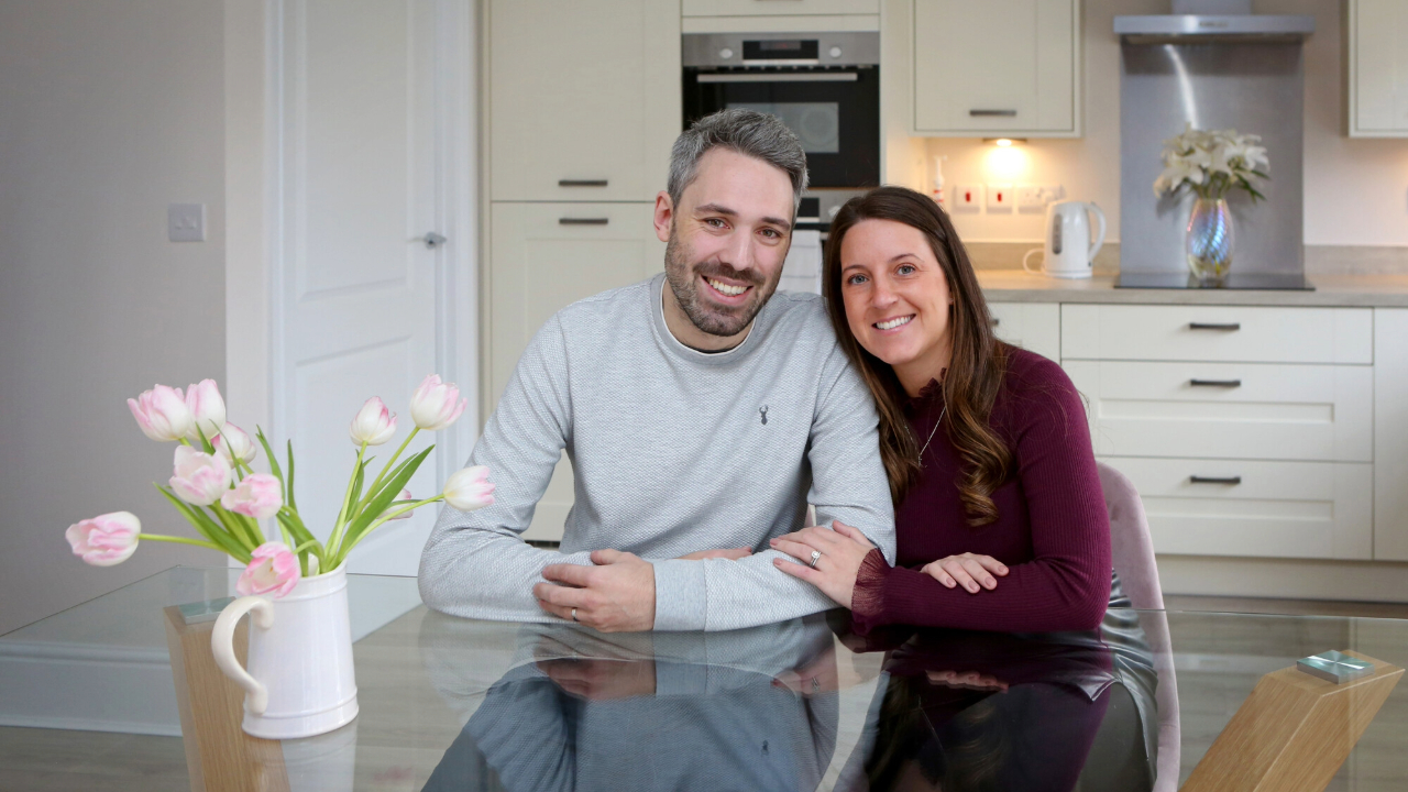 Couple sitting at in their new kitchen, with tulips in a jug on the table