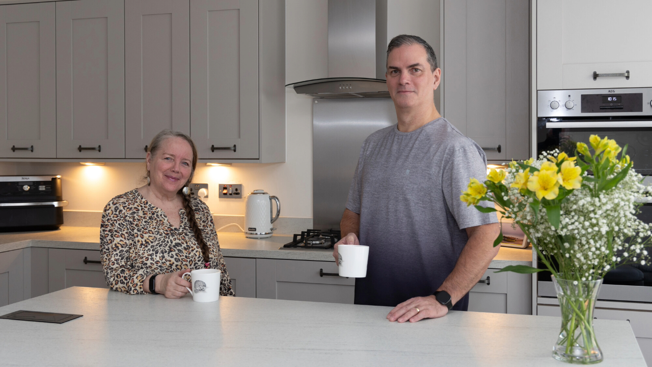 Couple enjoying hot drinks in their new kitchen, with a beautiful yellow bouquet on the kitchen island
