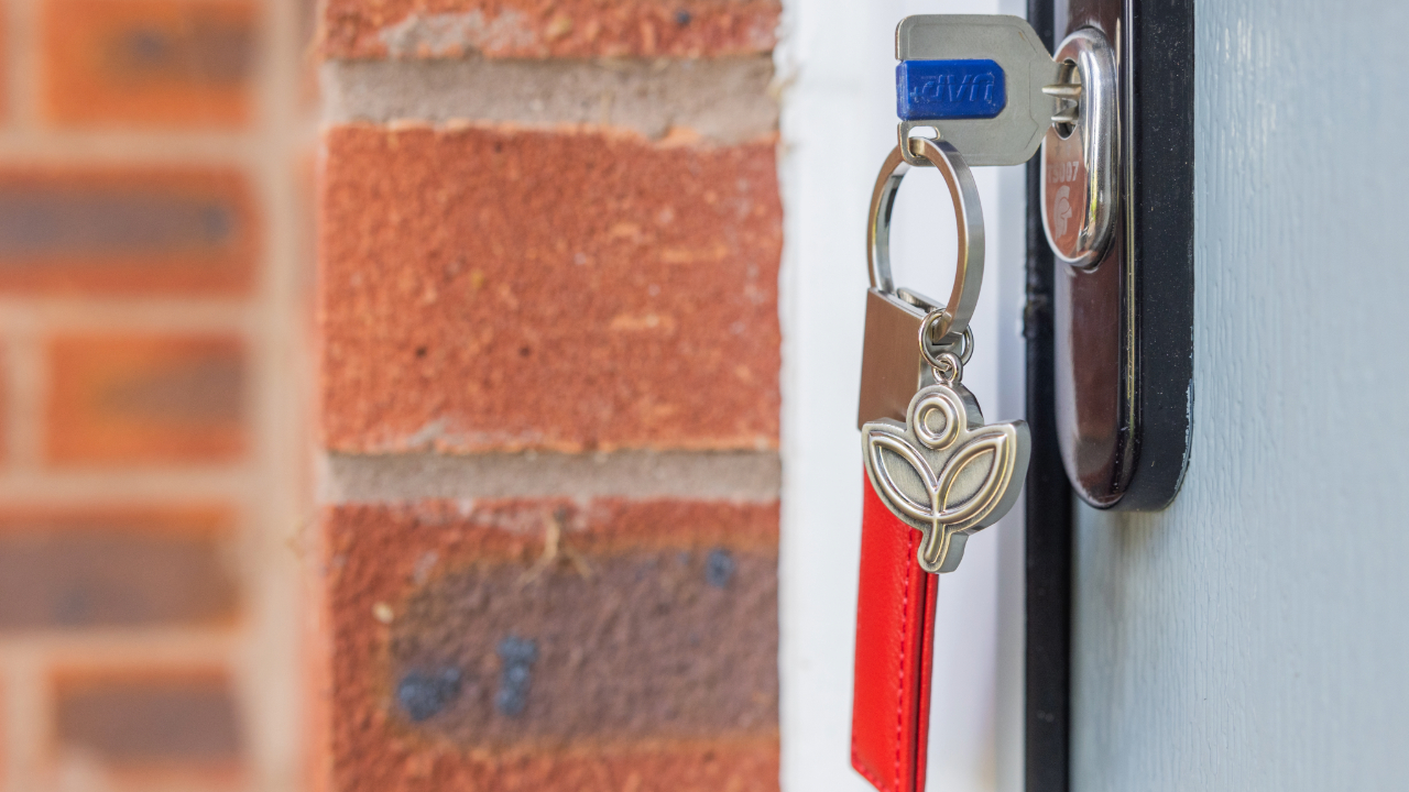 Housekeys with a Redrow keychain in a front door lock