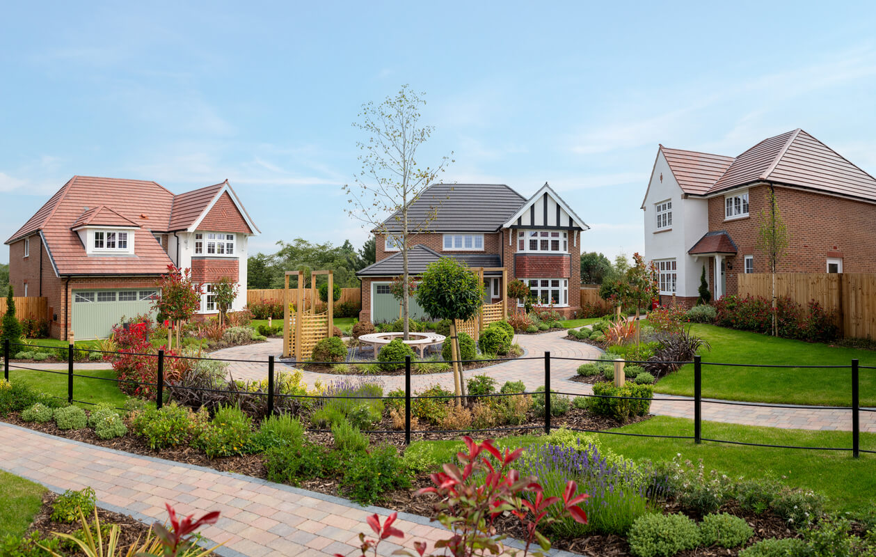 A well looking pair of houses in a sunny day with gardens in front