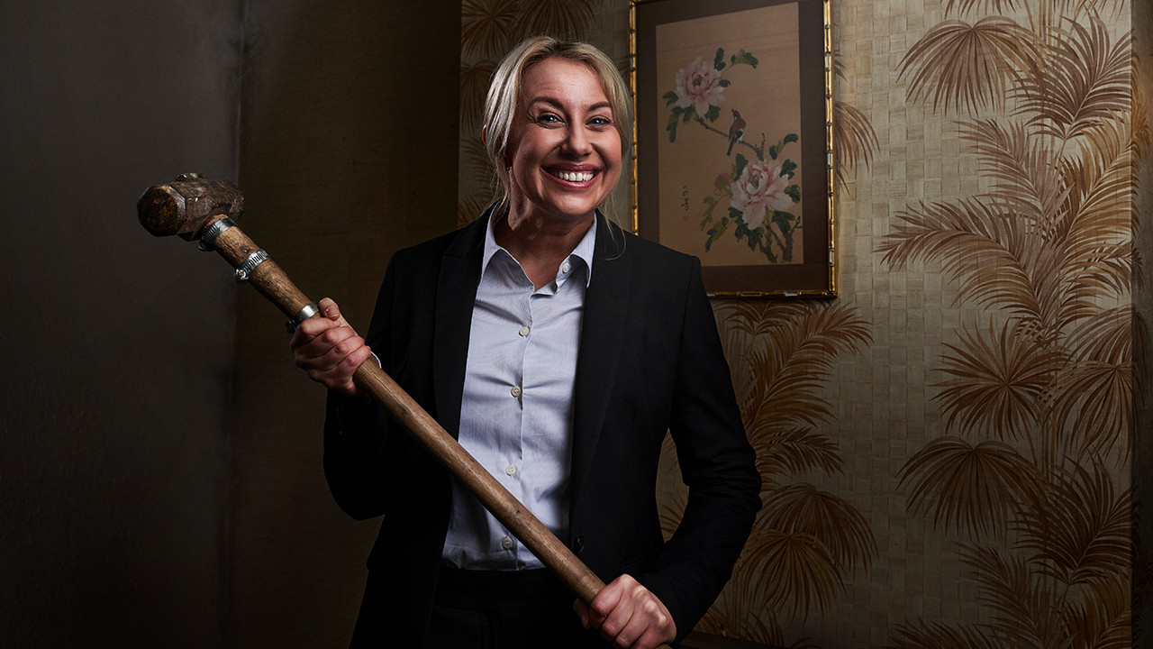 Suited woman with large hammer ready for home renovation