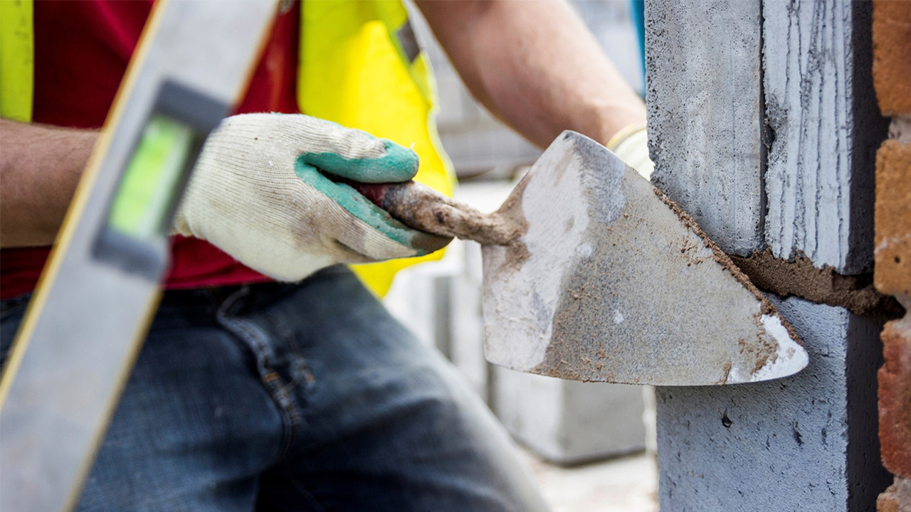 A bricklayer using a trowel to get a smooth finish on some brickwork