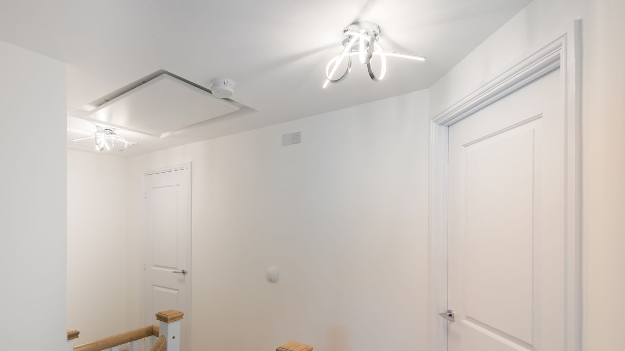 Freshly-painted white upstairs hallway with modern light fittings