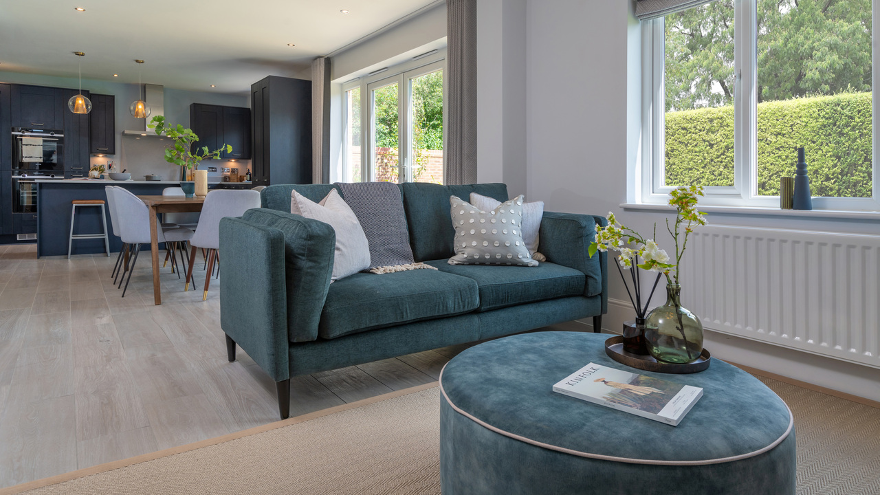 Family area with a teal velvet sofa and pouffe in an open plan living space
