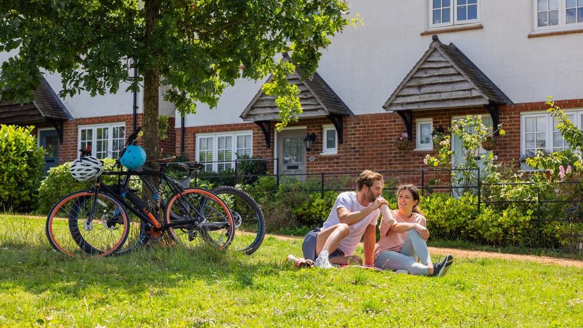 Couple with bikes relaxing on the grass outside some Heritage homes
