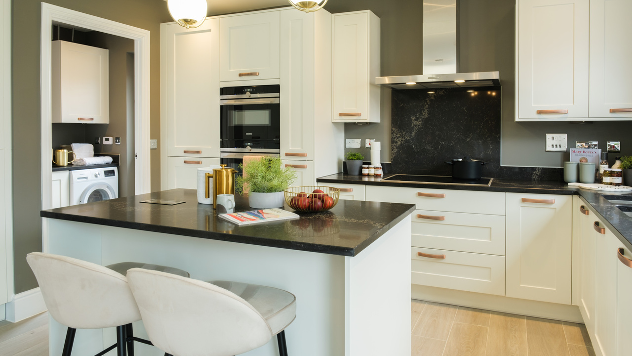 White kitchen and island with black marble worktops and olive green walls