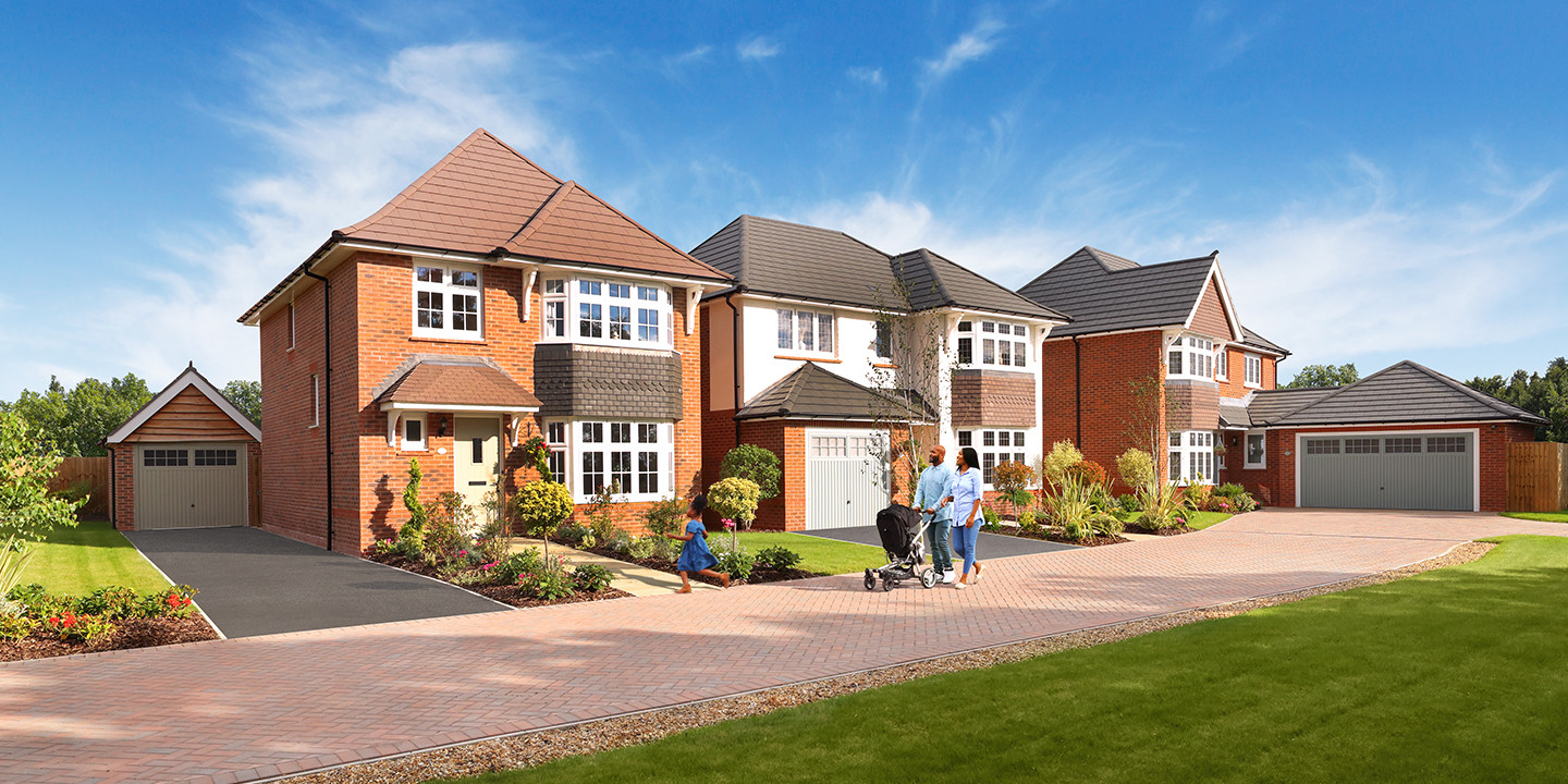 Family with a young girl pushing a pram outside some Redrow homes