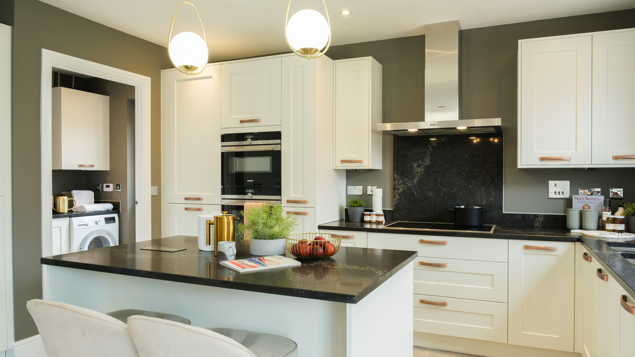 White kitchen and island with black marble worktops and olive green walls