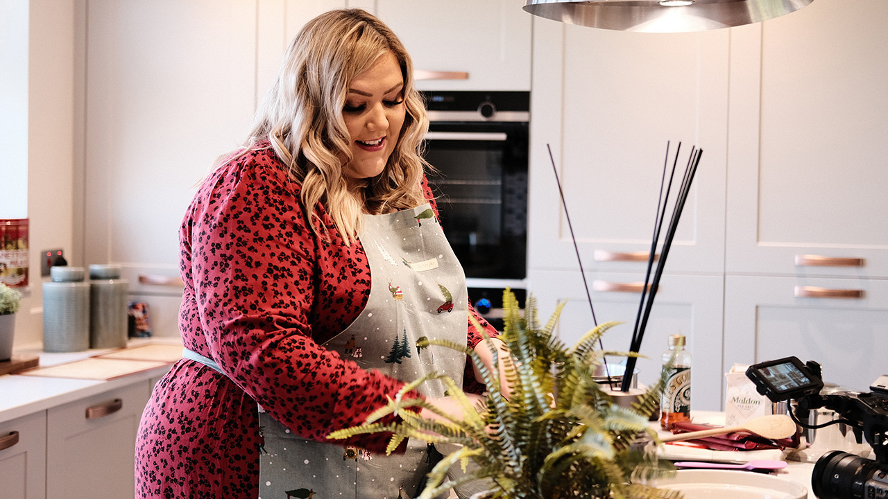 Woman in a red dress adding ingredients to a mixing bowl