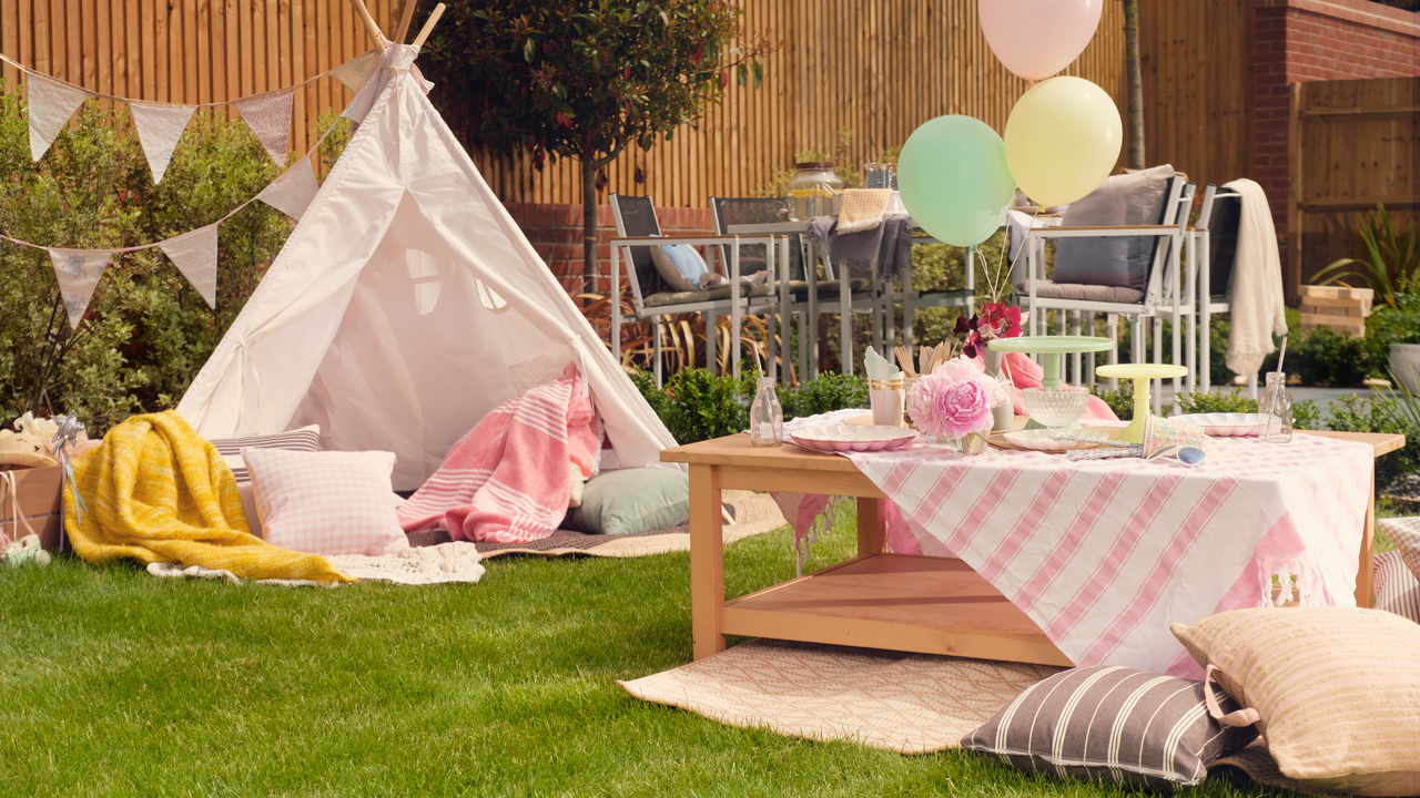 Garden ready for a party with pink teepee, bunting and pastel-coloured balloons