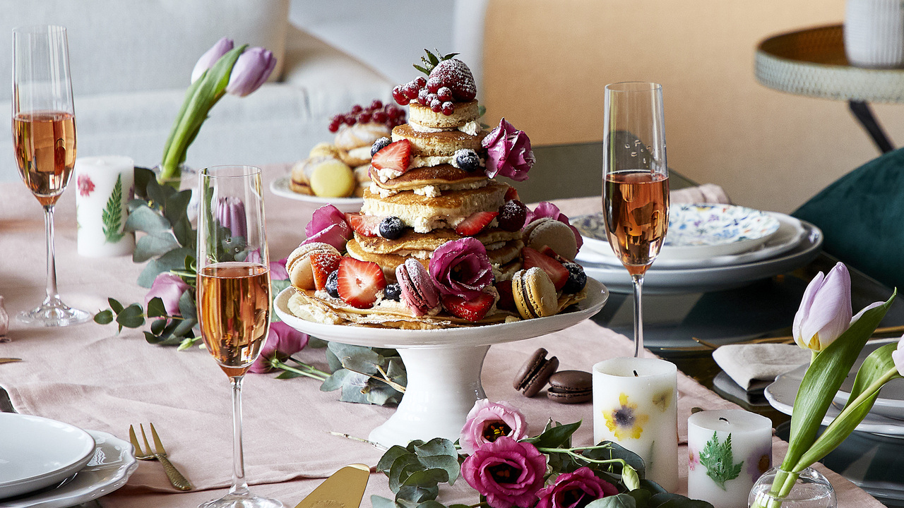 Tower of pancakes with fresh berries and glasses of sparkling rose