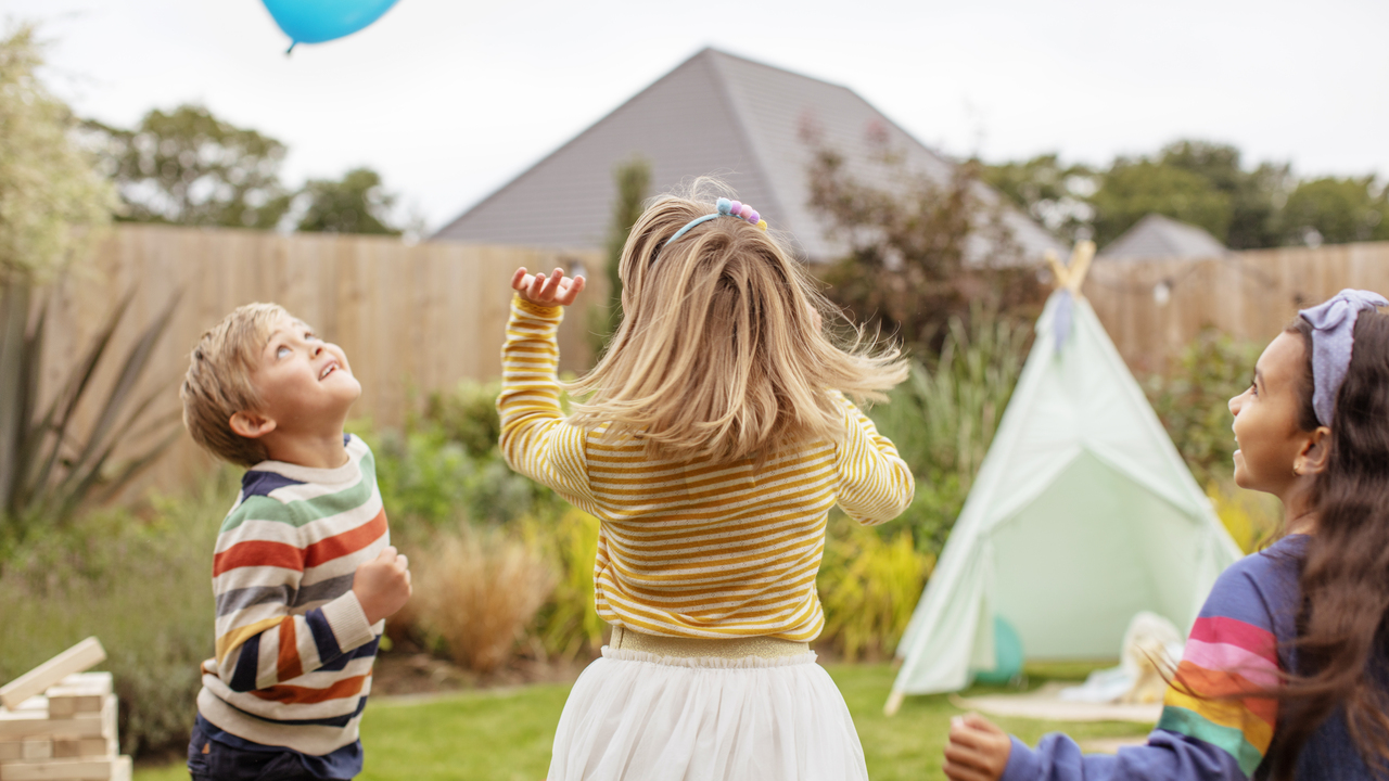 Two children playing with a balloon in a garden