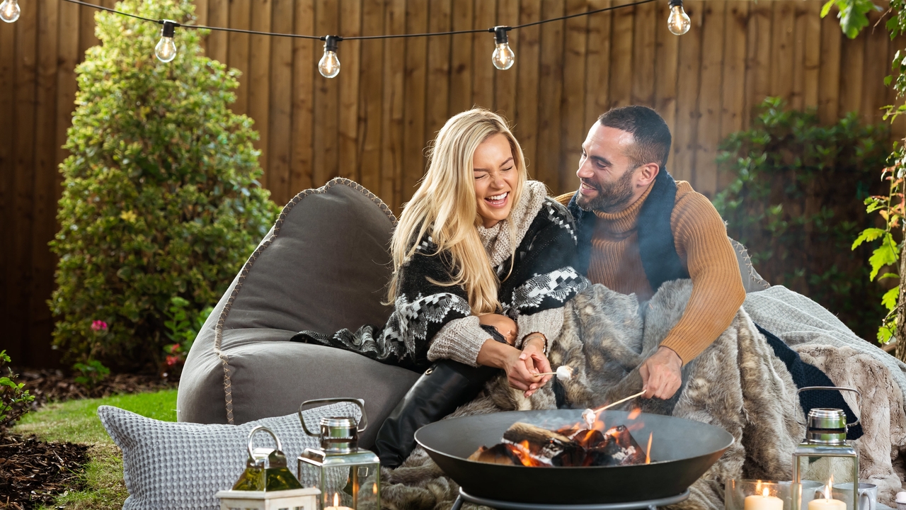 Happy couple sitting on a beanbag and toasting marshmallows
