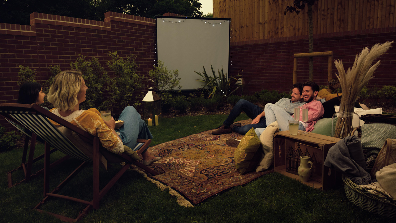 Friends sat in the garden around an outdoor cinema screen