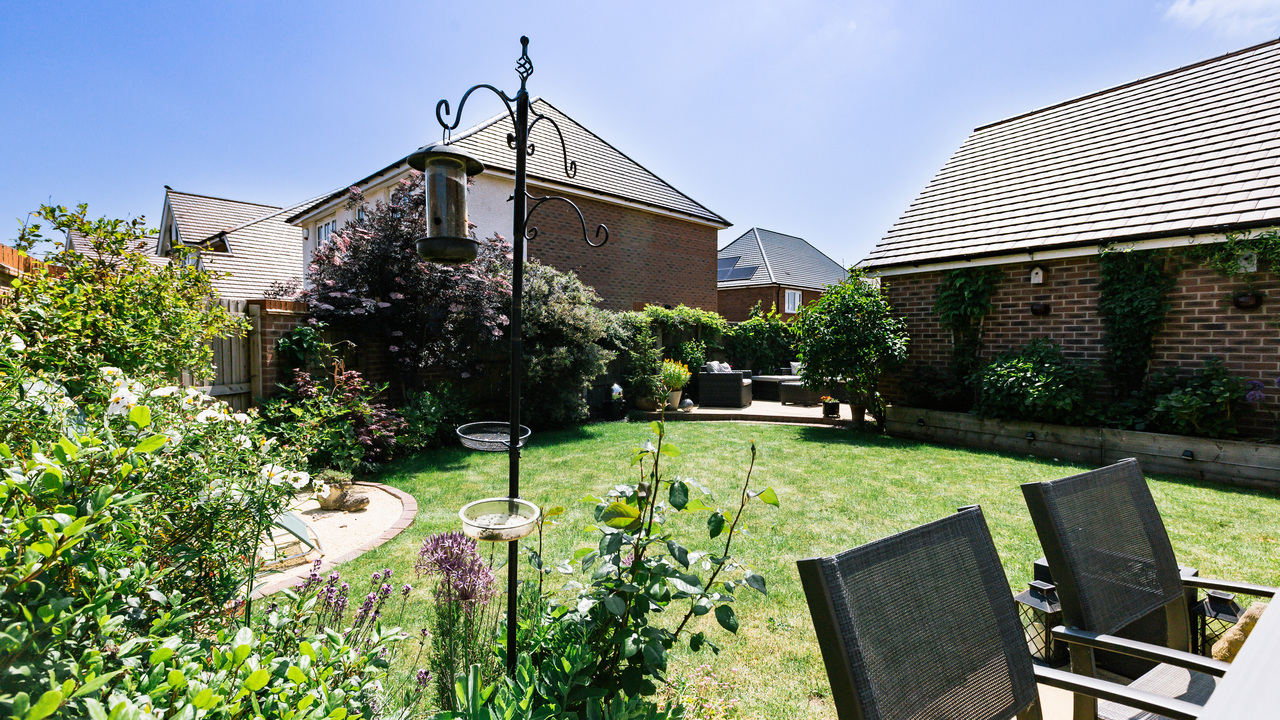 Beautifully maintained garden with a mix of plants, a bird feeder and garden furniture